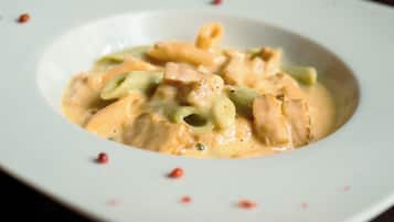A bowl of pasta with a creamy sauce and green vegetables.