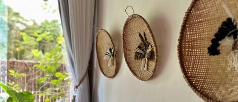 Tres tapices de pared tejidos con diseños de pájaros, una ventana con cortinas y vistas a zonas verdes al exterior.