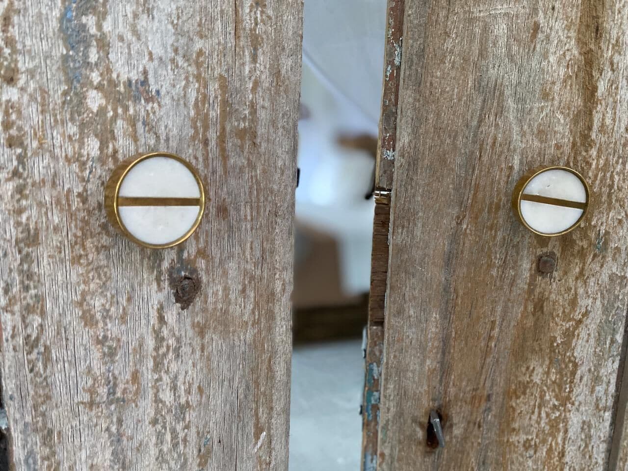 Una puerta de madera rústica con dos pomos blancos, con detalles dorados.
