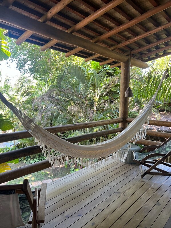 A hammock under a wooden pergola with a view of lush greenery. - Soleluna Casa Pousada (Porto Seguro)