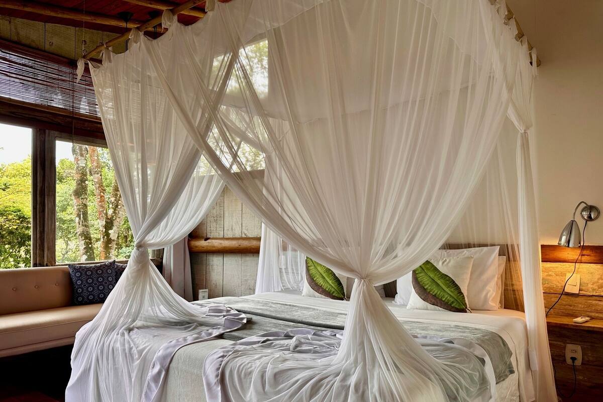 A bedroom with a canopy bed, a wooden headboard, and a bedside table with a lamp.