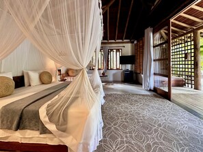 A bedroom with a canopy bed, a patterned rug, and a view of the outside. - Soleluna Casa Pousada (Porto Seguro)