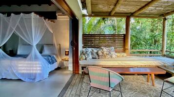Un dormitorio con una cama con dosel, un sofá con cojines estampados y una mesa de madera.