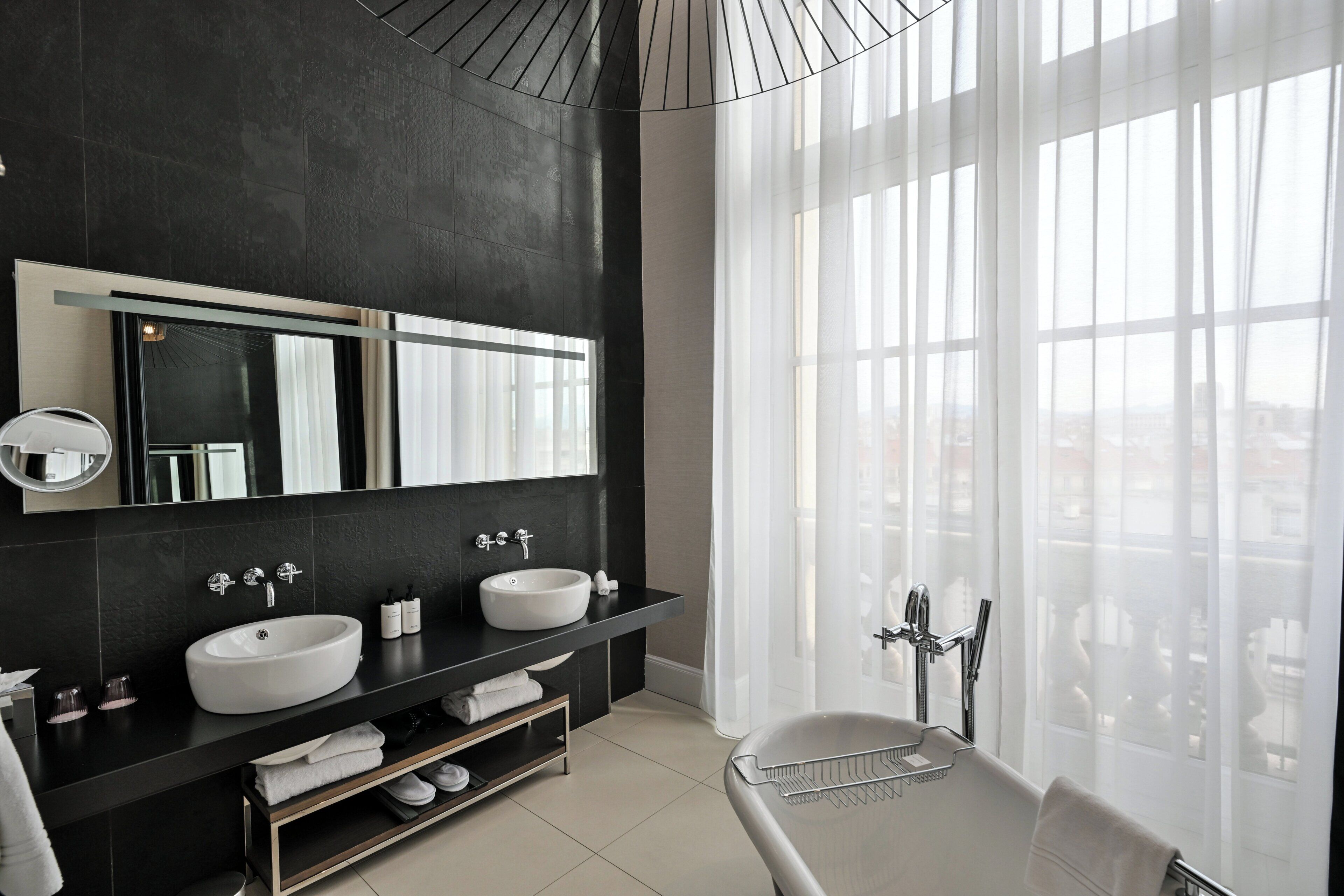 A modern bathroom with two sinks, a large mirror, and a bathtub.