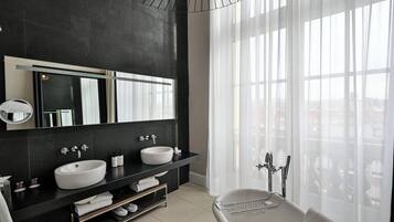 A modern bathroom with two sinks, a large mirror, and a bathtub.