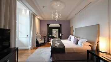 A modern hotel room with a large bed, a television, a desk, and a chandelier.