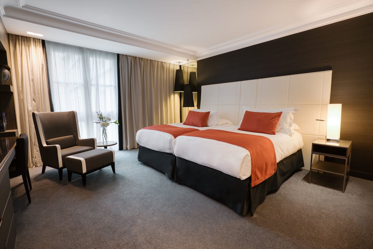 Une chambre d’hôtel avec un grand lit, deux tables de chevet, une chaise et un bureau.