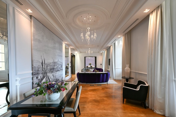 A hallway with a dining table, chairs, a purple sofa, and a chandelier. - InterContinental Marseille - Hotel Dieu by IHG (Marseille)