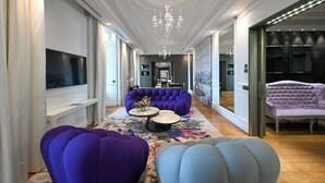 A spacious hallway with a large seating area featuring purple and blue sofas, a chandelier, and a flat-screen TV mounted on the wall. - InterContinental Marseille - Hotel Dieu by IHG (Marseille)