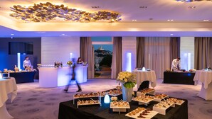A hotel lobby with a reception desk, tables with food, and a view of a cityscape. - InterContinental Marseille - Hotel Dieu by IHG (Marseille)