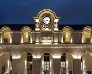 Un edificio con un reloj destacado, ventanas en arco y detalles arquitectónicos clásicos.