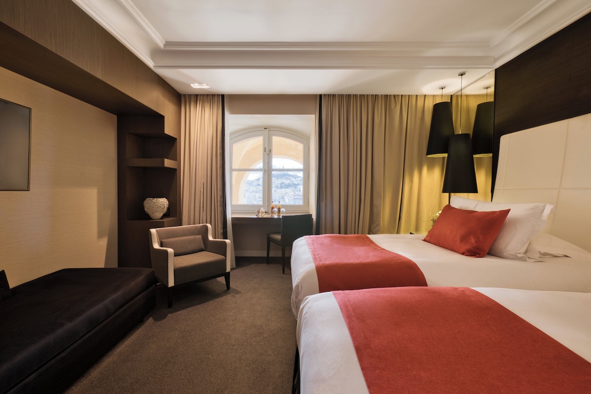 Habitación de hotel con dos camas, un escritorio, una silla y un sofá.