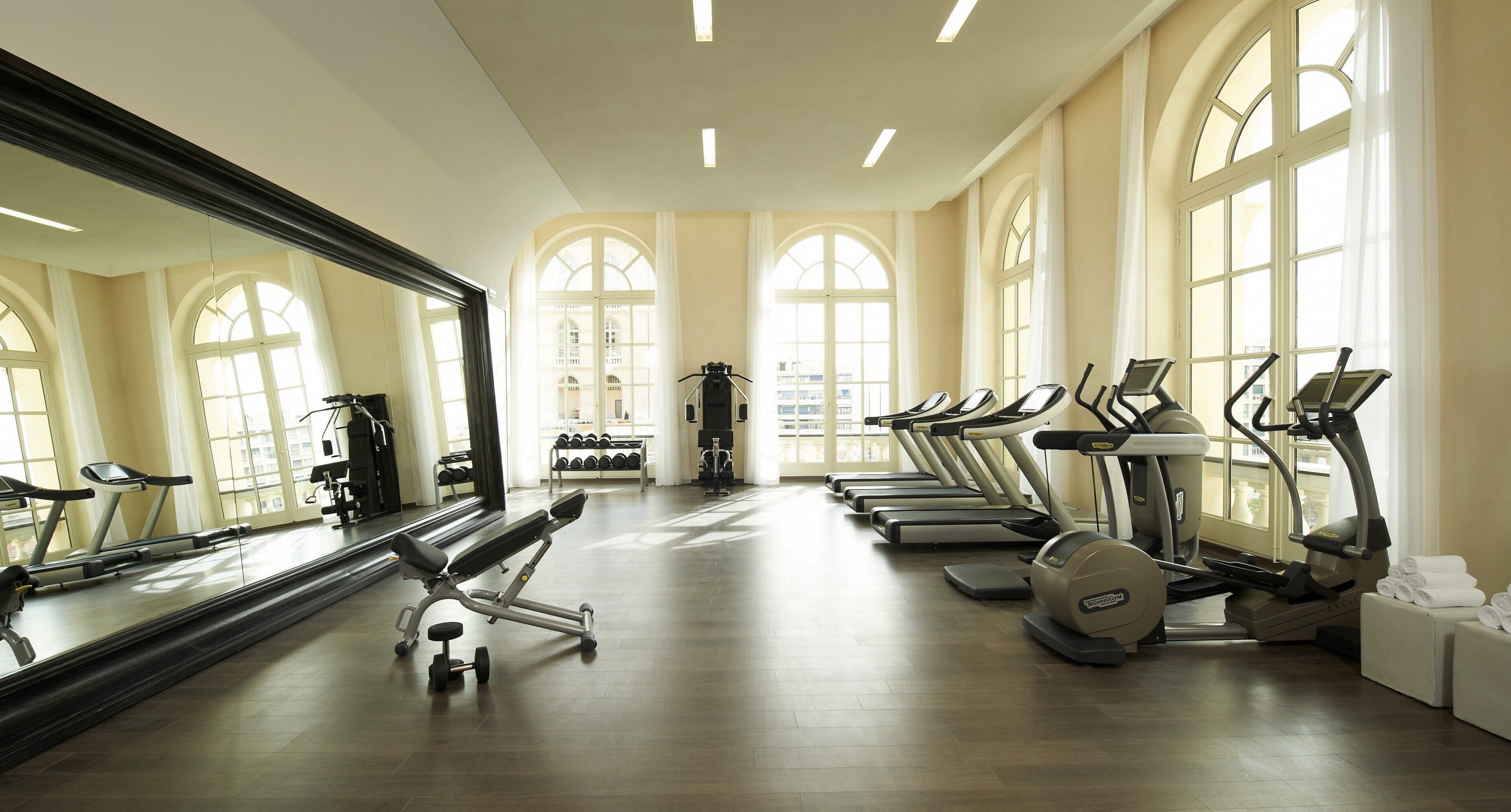 Un gimnasio con cintas de correr, pesas y un espejo grande.