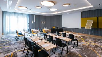 A conference room with tables, chairs, a projector screen, and a flip chart stand.