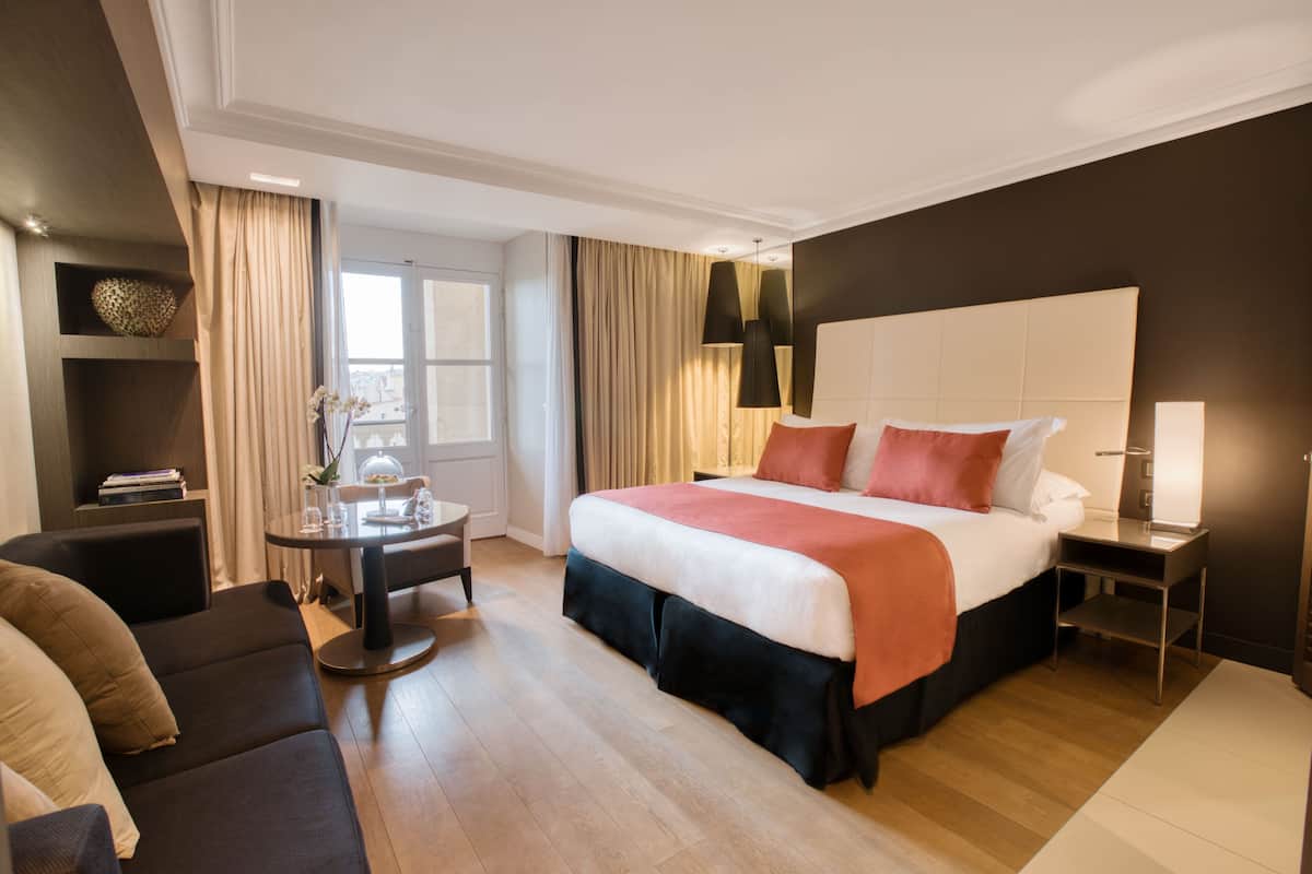 Une chambre d’hôtel avec un grand lit, un bureau, une chaise et un canapé.