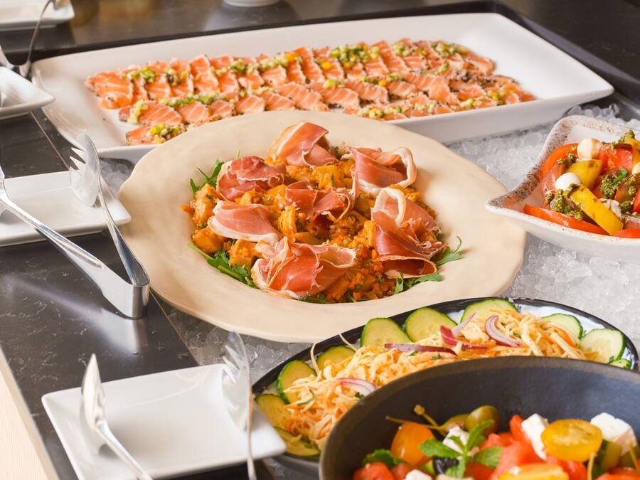 A buffet with various dishes, including salads, pasta, and seafood.