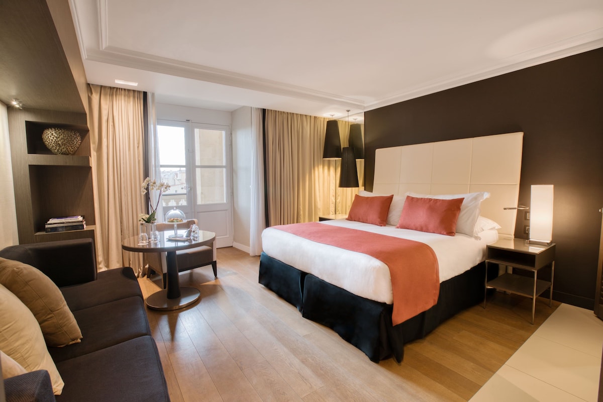 Una habitación de hotel con cama, escritorio, silla y sofá.