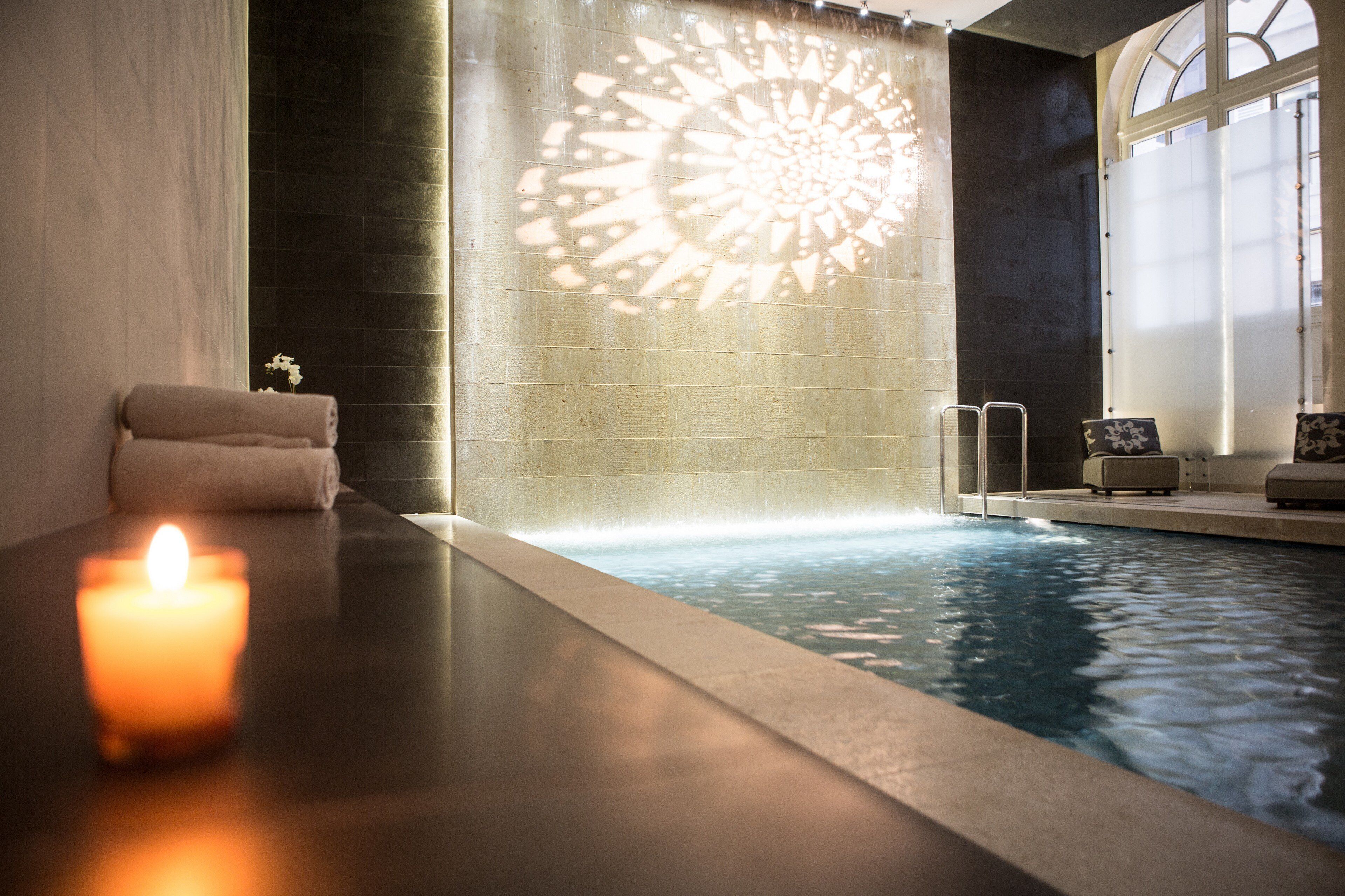 Wellnessbereich mit Whirlpool, Kerze und dekorativer Wand.
