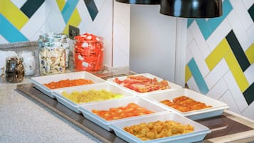 Un bufé con diversos alimentos en bandejas, como carnes, verduras y otros platos.