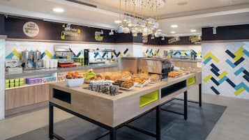 Zona de bufé con una variedad de alimentos, incluyendo frutas, pasteles y bebidas.