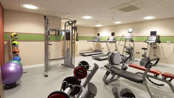 A gym with treadmills, elliptical machines, a bench press, and a rack of medicine balls.