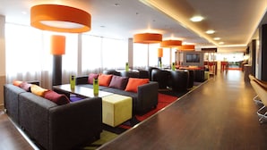 Un hall d’hôtel avec des canapés, une table basse et un écran de télévision.