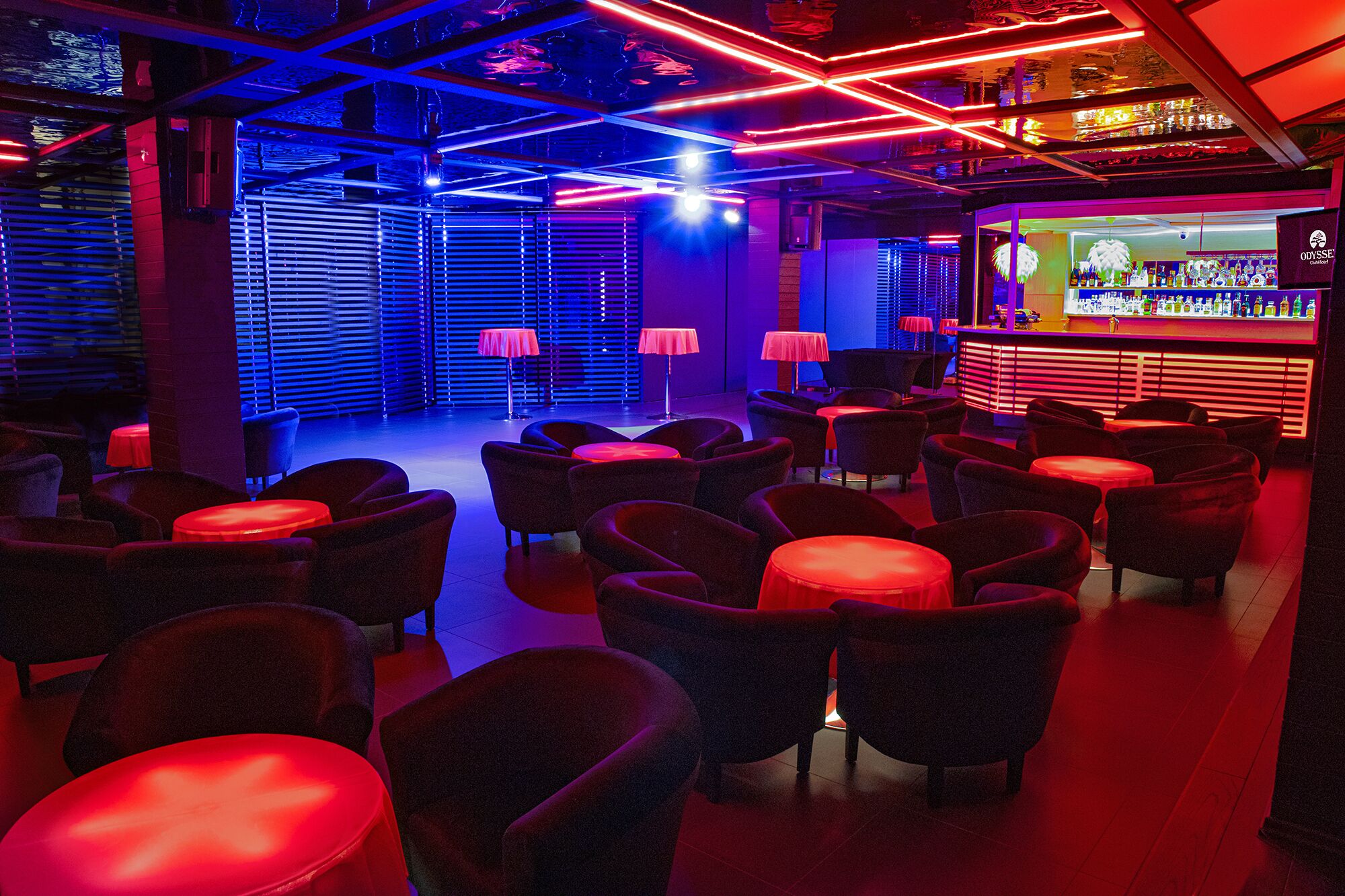 Un espace bar avec différents types de sièges, un comptoir et un éclairage d’ambiance.