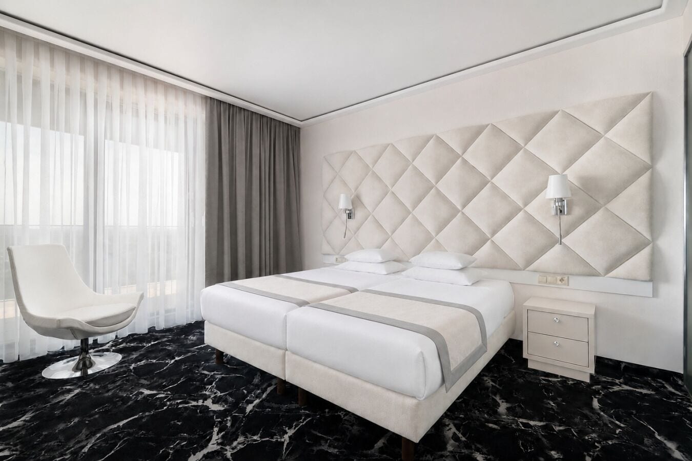 Habitación de hotel moderna con una cama grande, una silla, una mesita de noche y suelo de mármol.