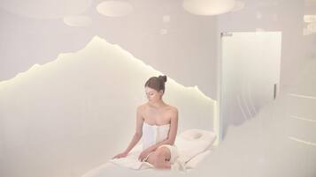 Une salle de spa avec un mur blanc dont le décor évoque une montagne, un lit et une porte.