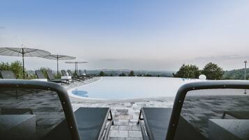 A pool area with lounge chairs and umbrellas, a clear view of the landscape, and a stone pathway leading to the pool.