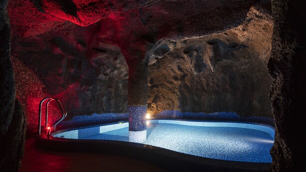 A spa area with a hot tub, tiled walls, and a red light fixture. - Odyssey ClubHotel Wellness & SPA (Maslów)
