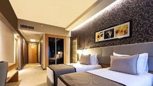 Habitación de hotel con dos camas, un espejo grande y un papel tapiz decorado.