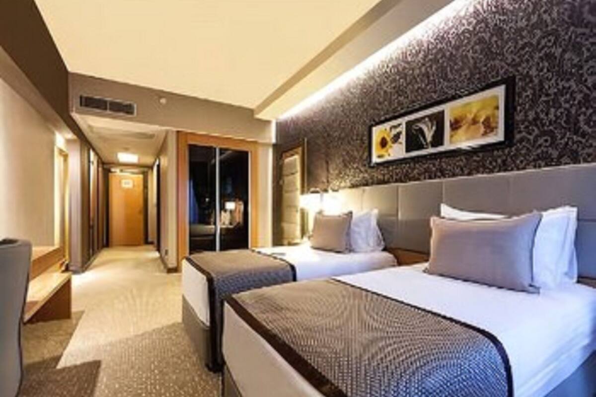 Habitación de hotel con dos camas, un espejo grande y un papel tapiz decorado.