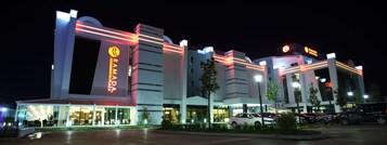 A modern building with a prominent 'RAMADA' sign, featuring a large entrance and multiple levels.