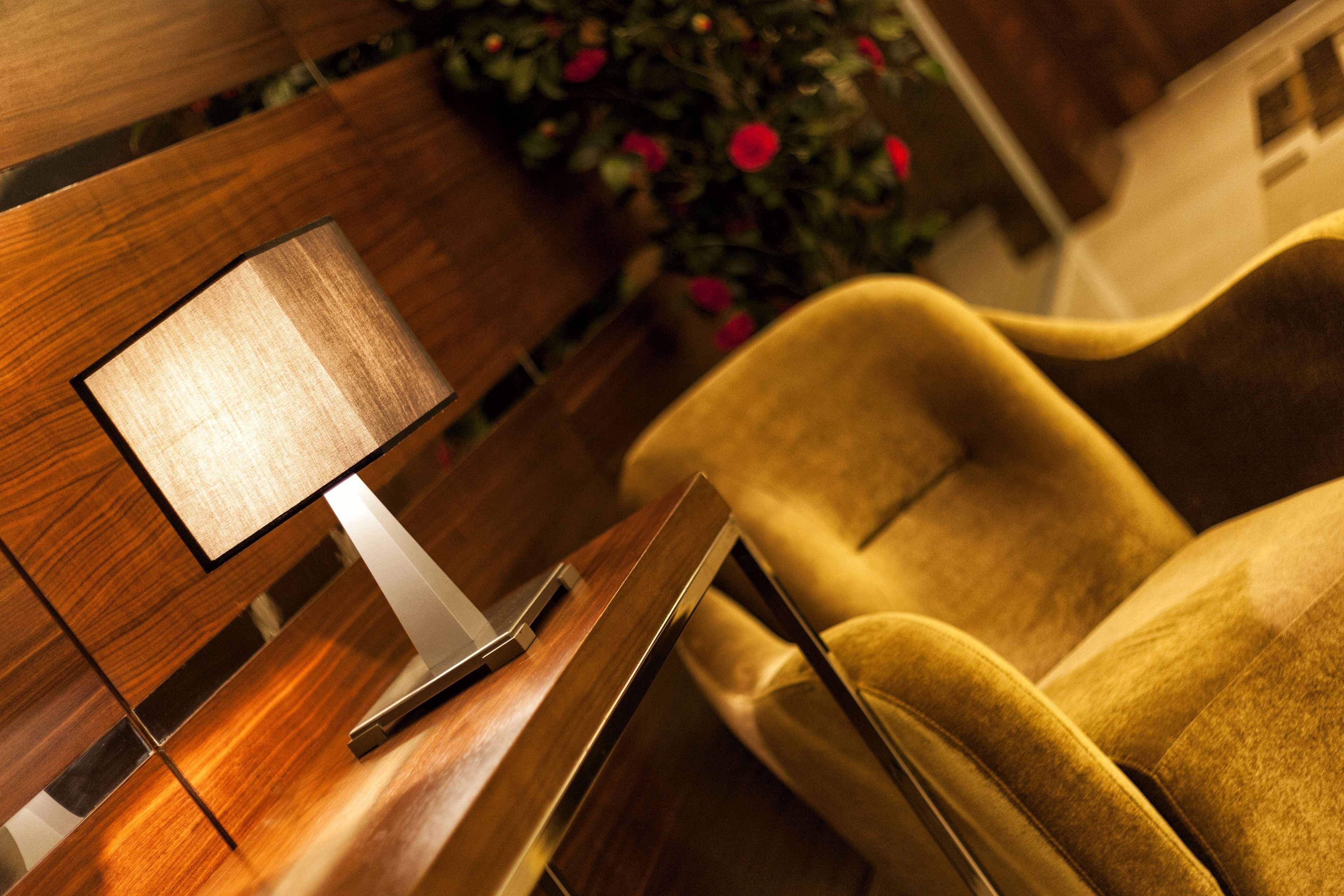 A modern interior with a wooden side table, a lamp, and a plush armchair.