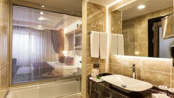 A modern bathroom with a large mirror, a bathtub, and a vanity with a sink.