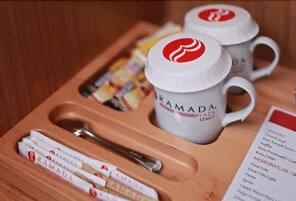 A tray with two white mugs labeled "RAMADA AZEAT PZMIT," a spoon, and several packaged snacks.