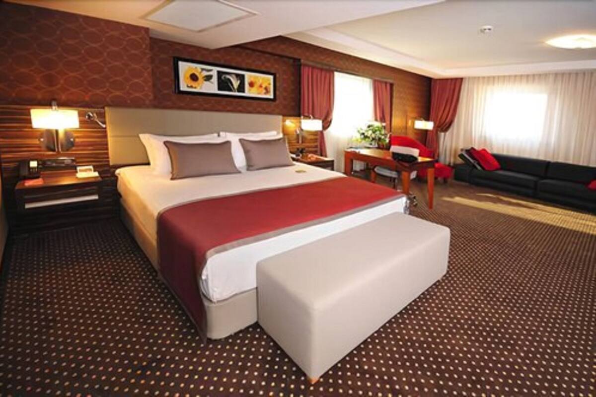 Una habitación de hotel con una cama grande, un sofá, un escritorio y una silla.