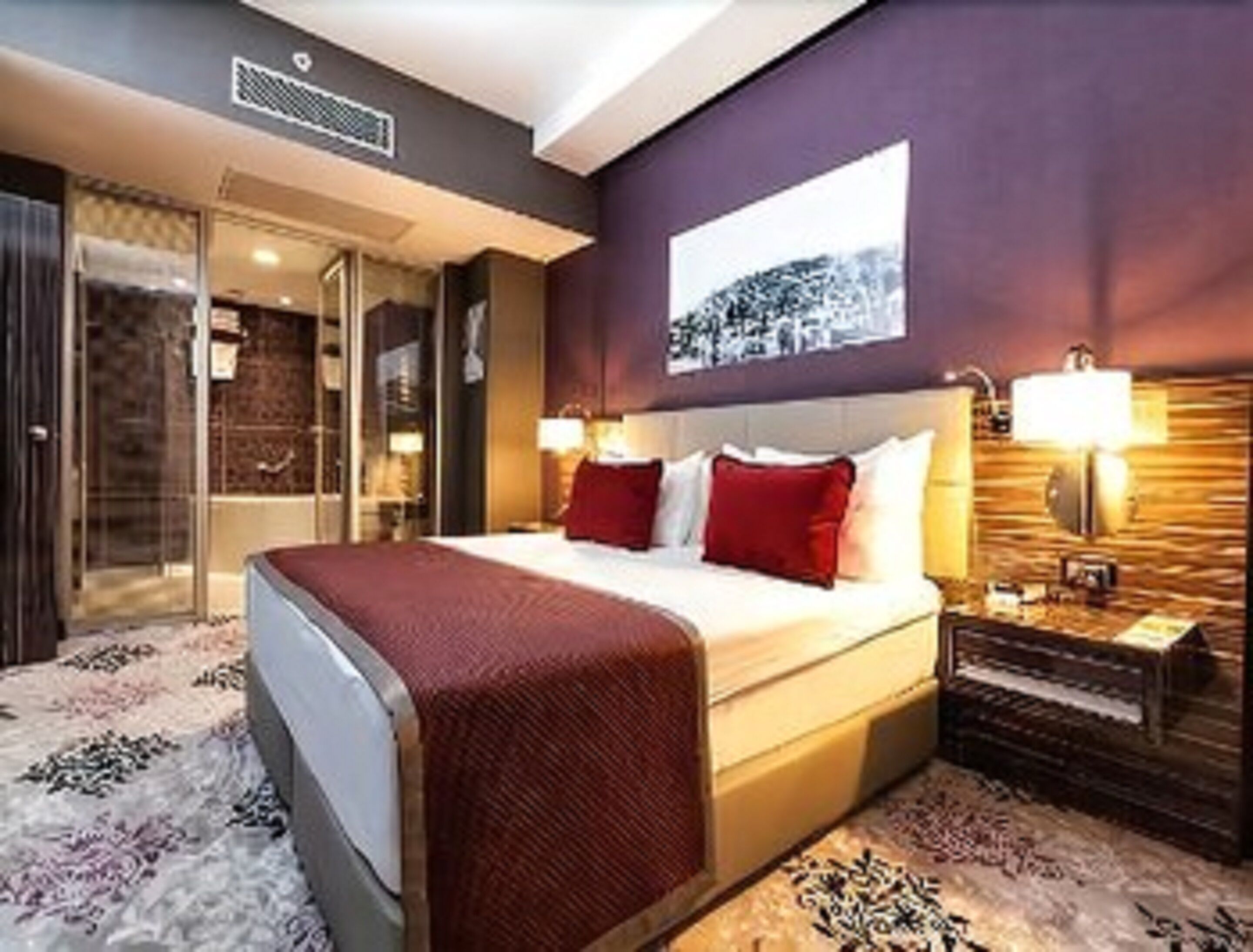 Una habitación de hotel con una cama grande, cabina de ducha de vidrio y cabecero de madera.