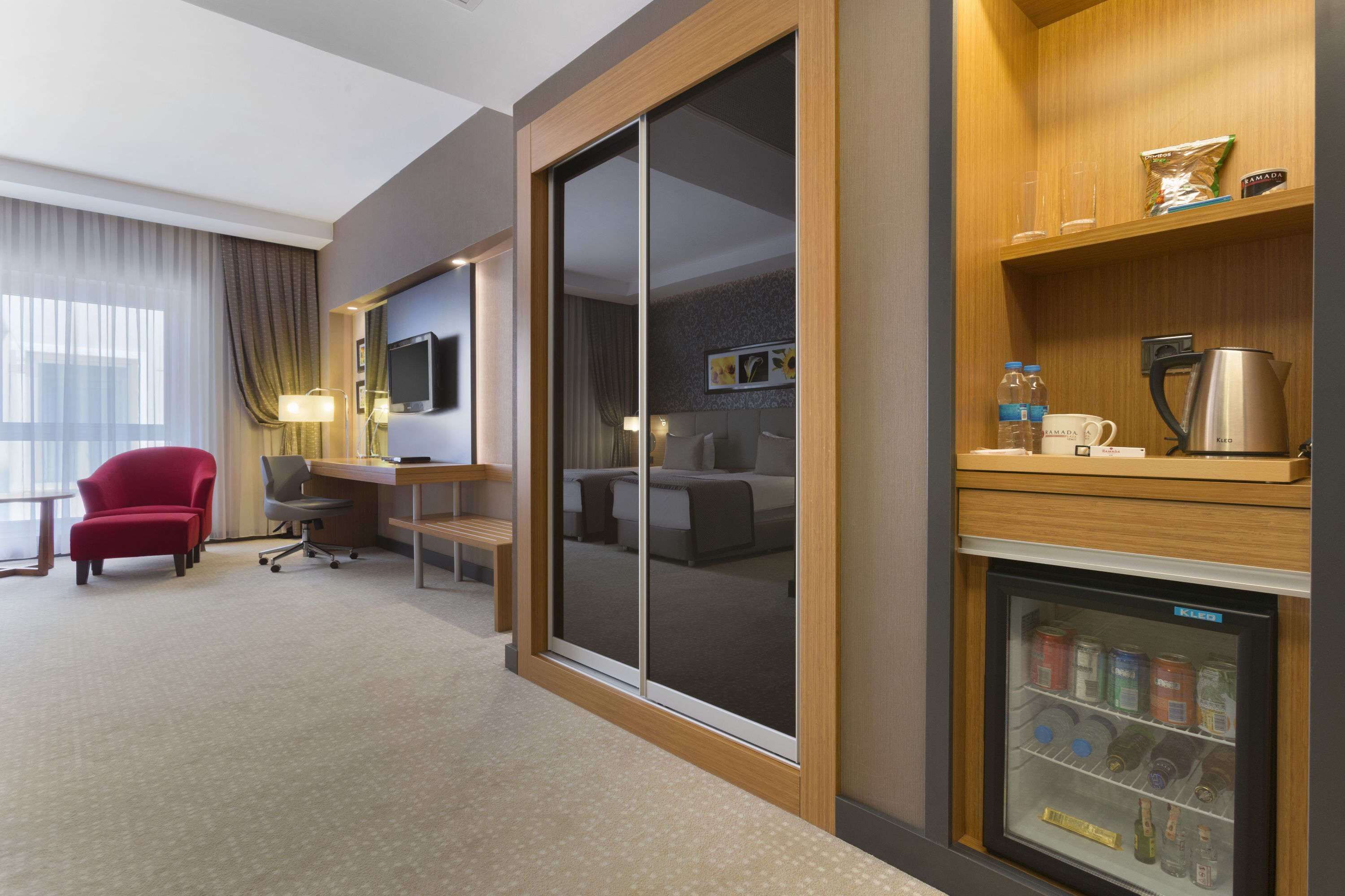 Een hotelkamer met een bureau, stoel en een minibar.