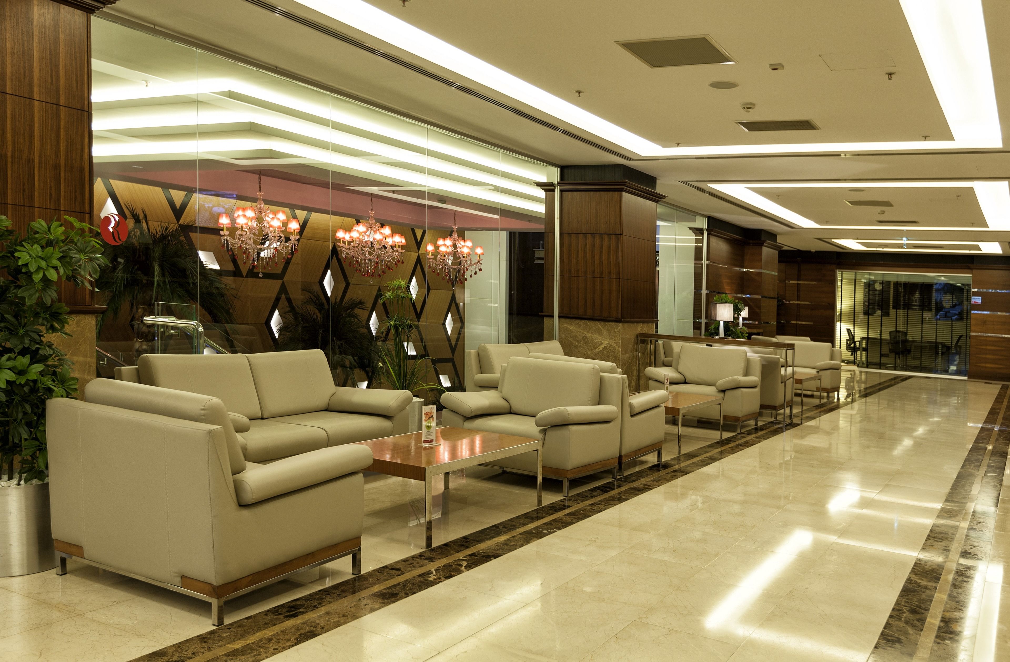 A modern lobby with a seating area, a reception desk, and a chandelier.