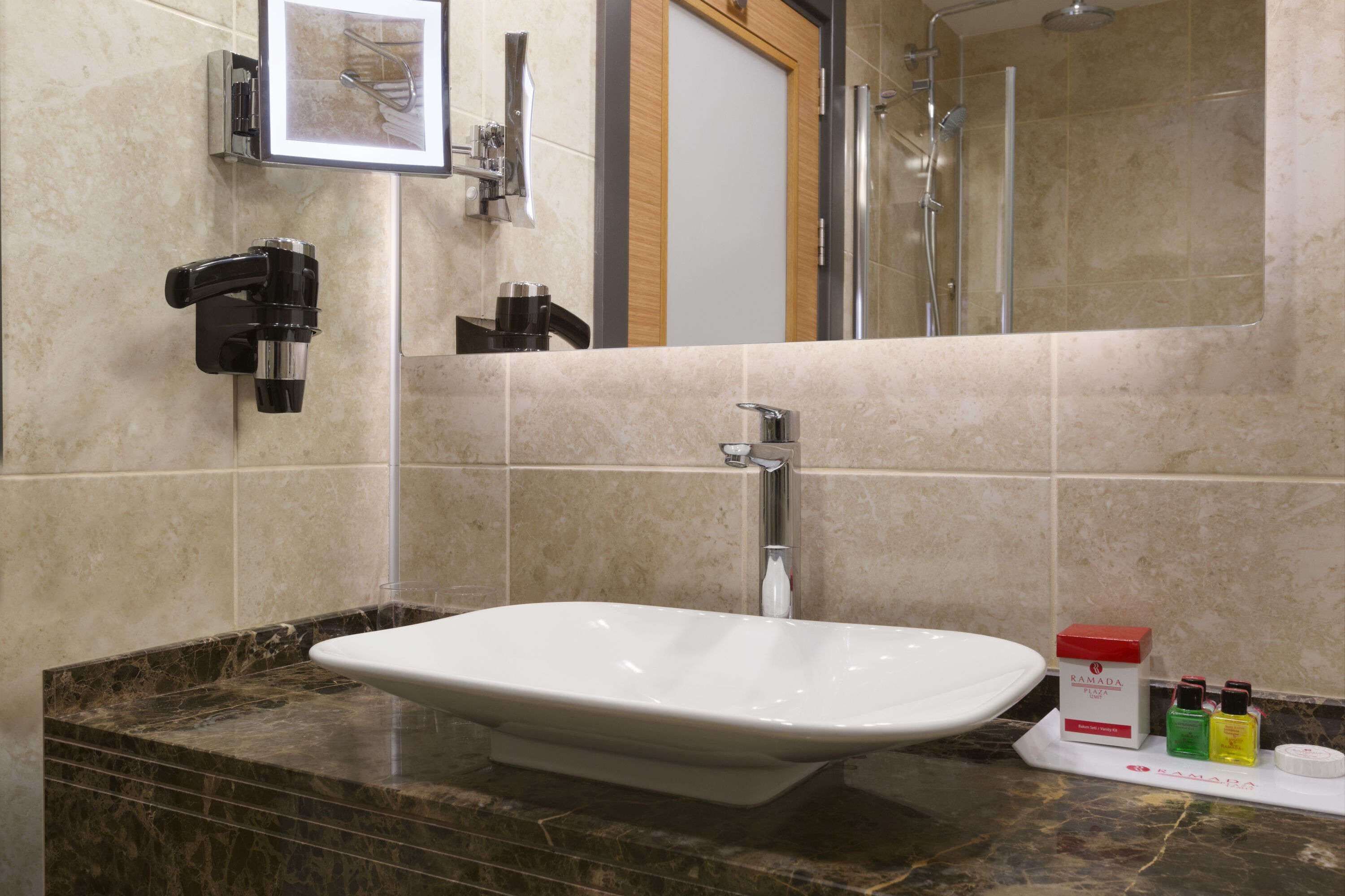 A bathroom with a white sink, a mirror, and a shower. There are toiletries on the counter.