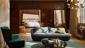 Une chambre d’hôtel moderne dotée d’un grand lit, d’un canapé, d’une table basse et d’un coin salon avec un fauteuil.