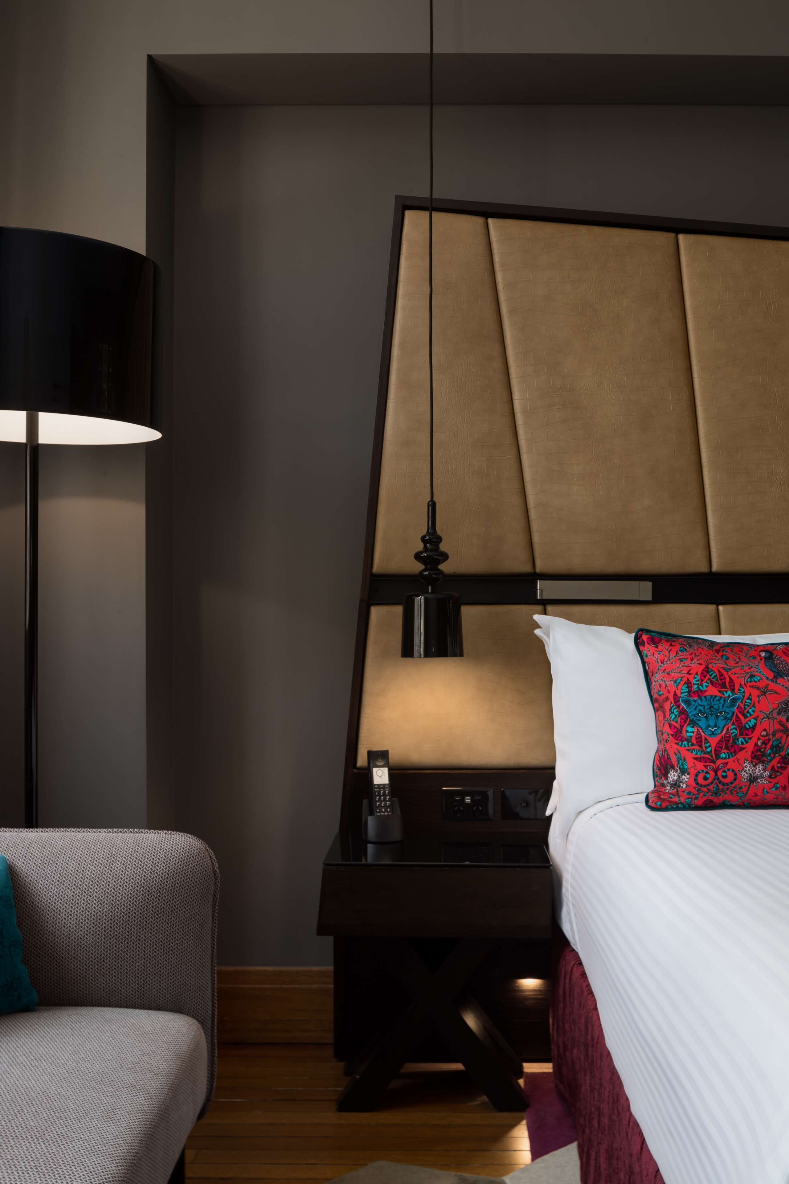 Ein Hotelzimmer mit Bett, Nachttisch, Lampe und Stuhl.