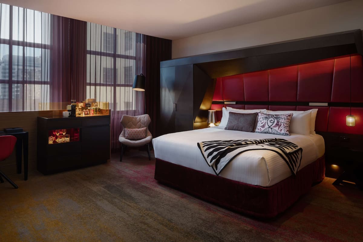 A modern hotel room with a large bed, a desk, and a chair.
