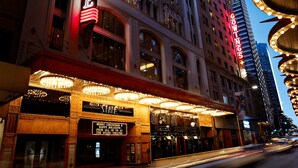 Un théâtre avec une enseigne lumineuse indiquant « COWING » et un panneau sur lequel on peut lire : « JOYEUX NOËL ET BONNES FÊTES DE TOUTE L’ÉQUIPE DU STATE THEATRE. »