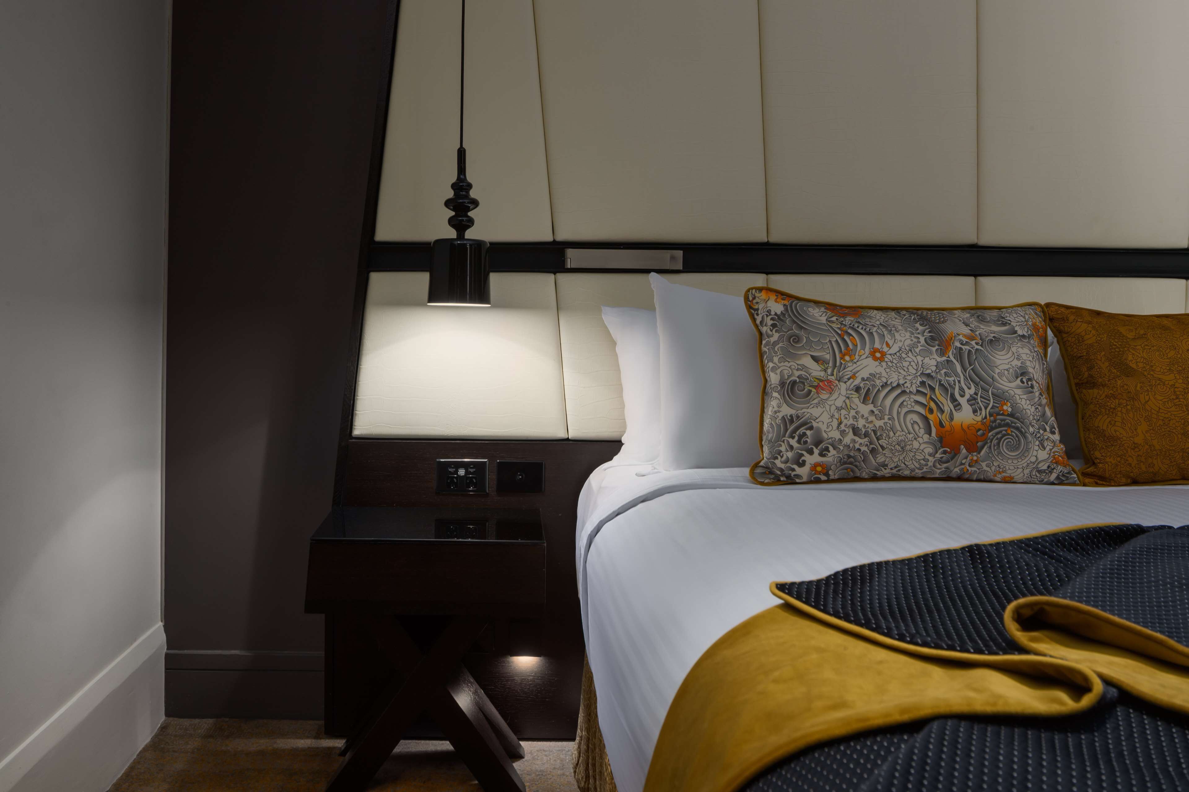 Ein Hotelzimmer mit Bett, Nachttisch, Lampe und Beistelltisch.