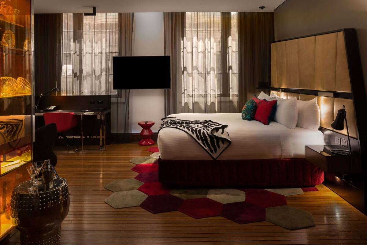 A modern hotel room with a large bed, a desk, and a television.