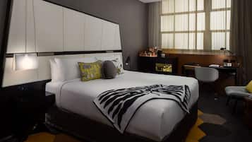 A modern hotel room with a large bed, a desk, and a chair.
