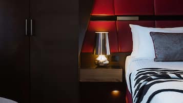 Quarto com cama, mesa de cabeceira, abajur e guarda-roupa.